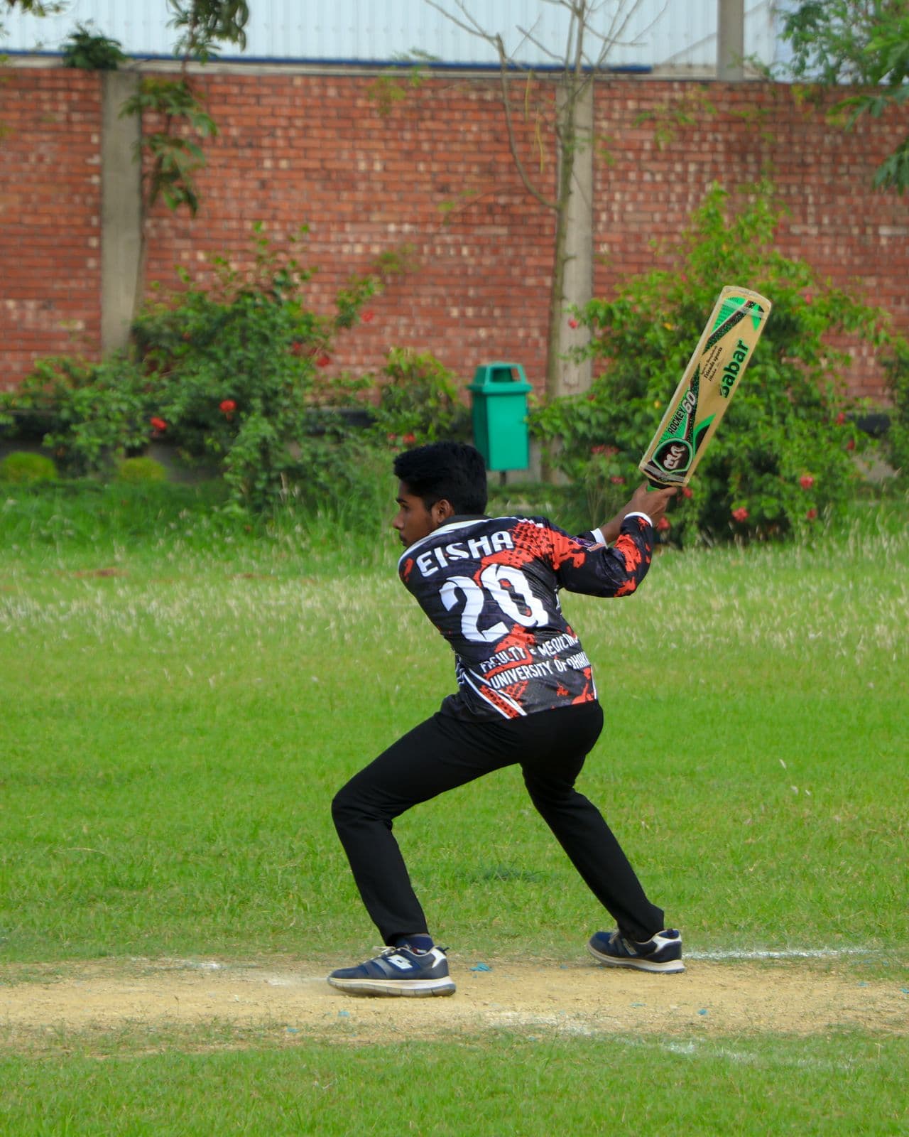 Wide view of a community cricket ground with fielders set in position during a daytime game