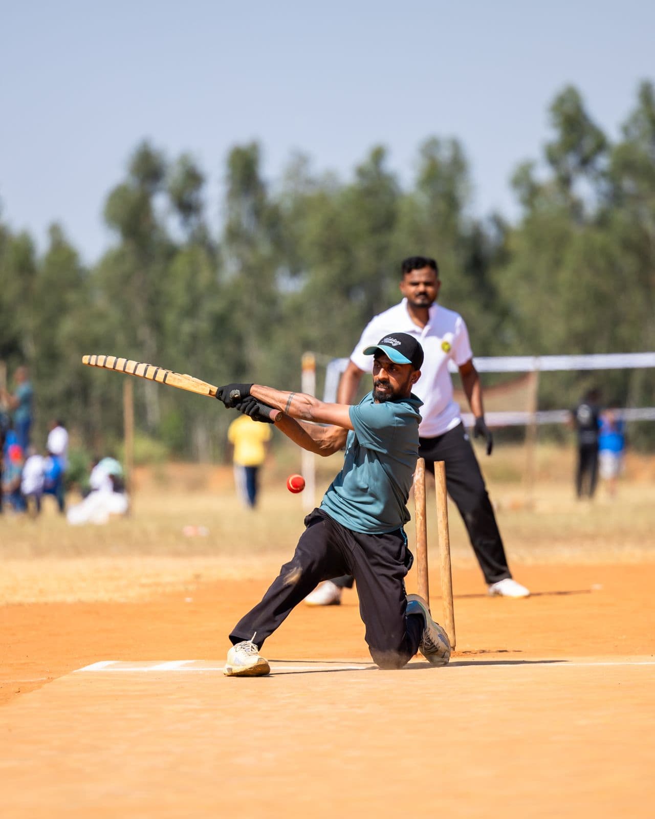 Spectators watching a local cricket match from the sidelines of a neighbourhood ground